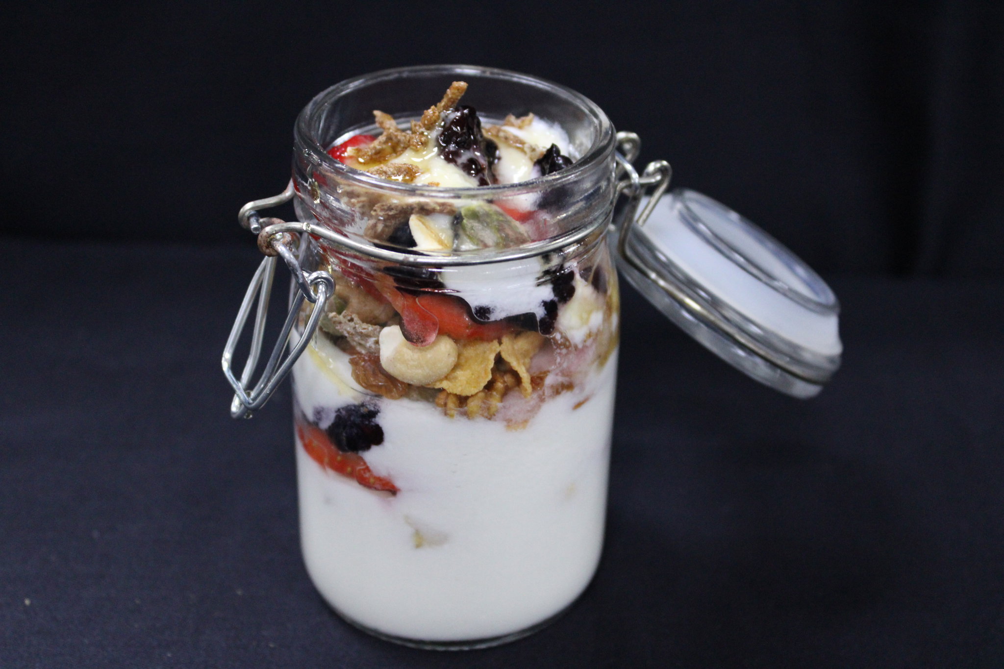 Plain yogurt mixed with granola, strawberries, blue berries topped with honey _0
