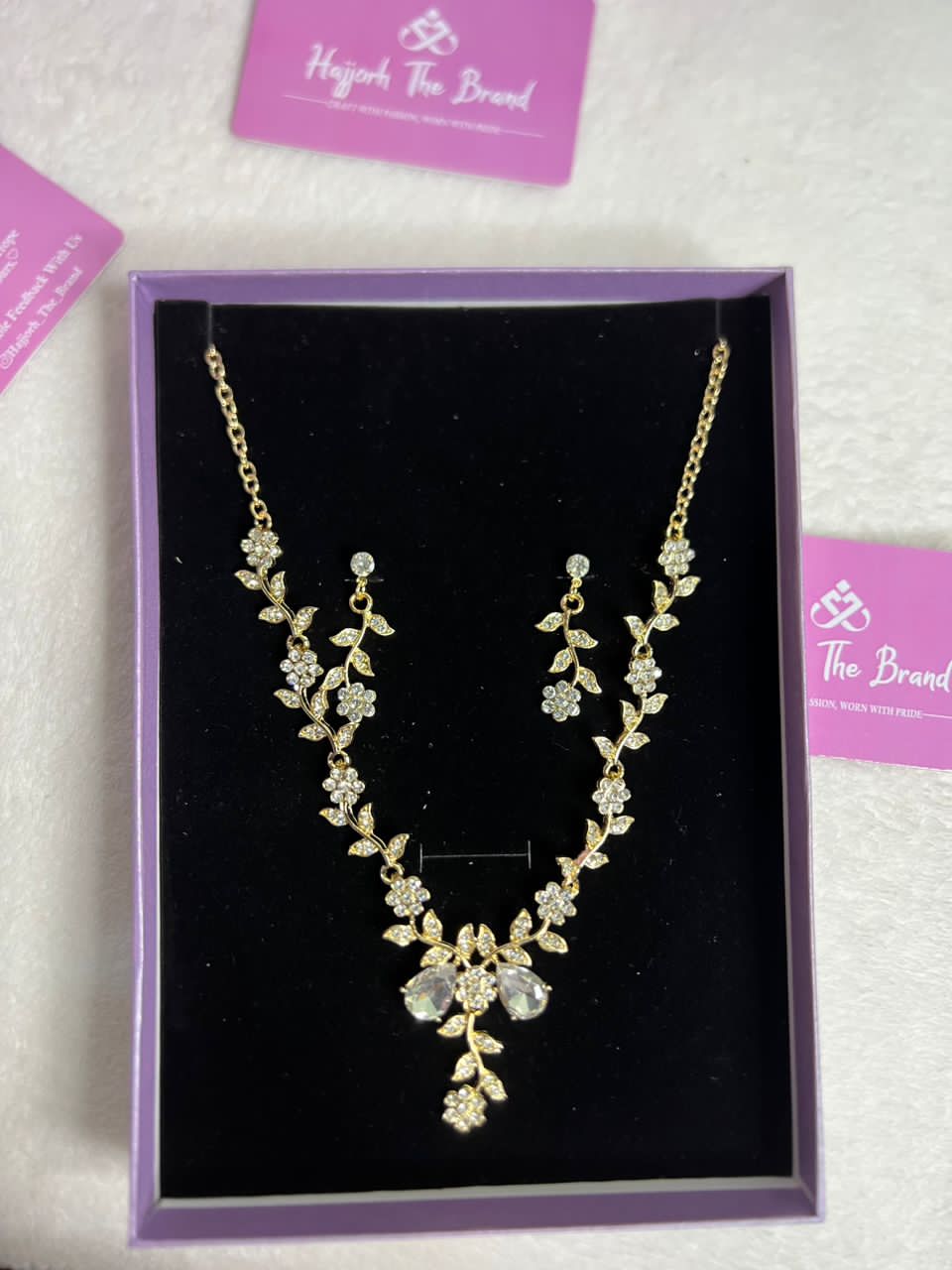 The necklace features a gold chain with diamond-studded flowers and leaves