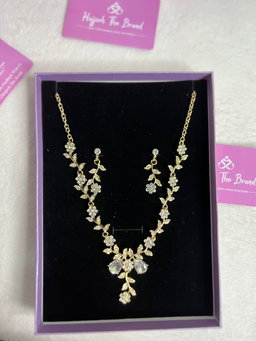 The necklace features a gold chain with diamond-studded flowers and leaves