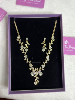 The necklace features a gold chain with diamond-studded flowers and leaves